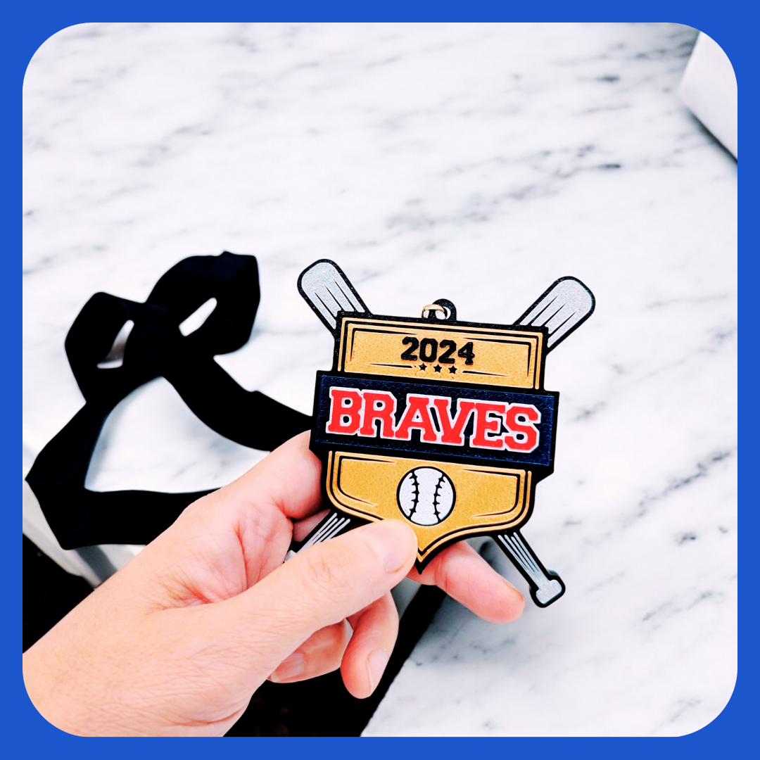 Custom baseball medal featuring a shield design with crossed bats, a black ribbon, and a bold team name. The gold background includes the year '2024' and a baseball icon. Perfect for teams and tournaments. Personalizable to match your team’s identity!