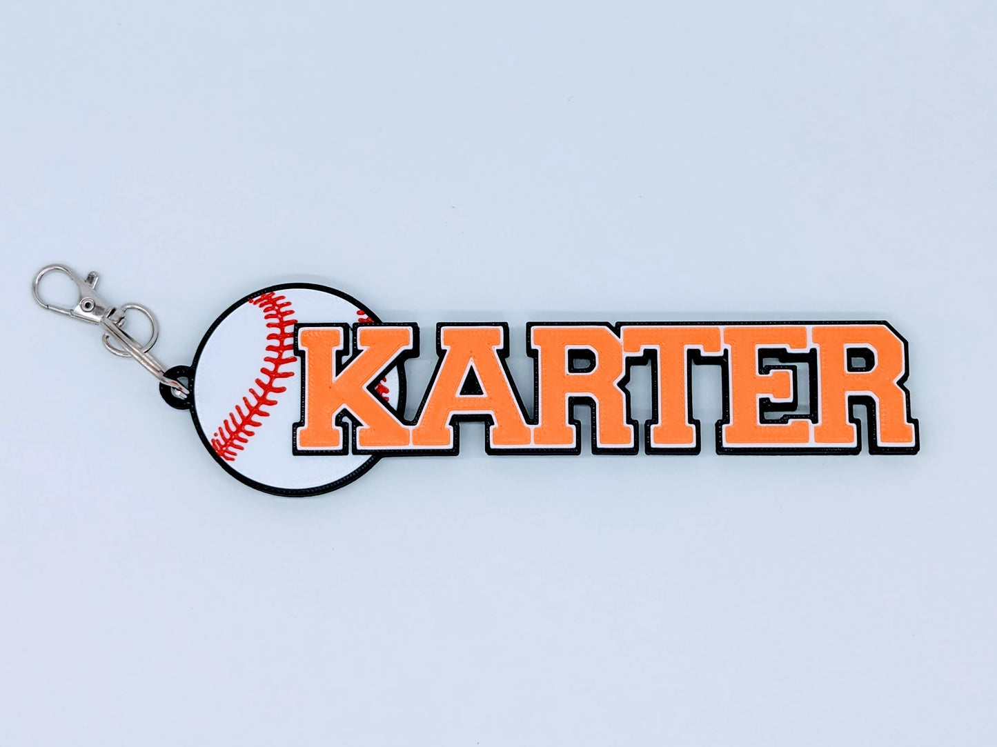 Bright orange baseball bag tag with custom engraved player number and name, ready to clip onto any sports bag.