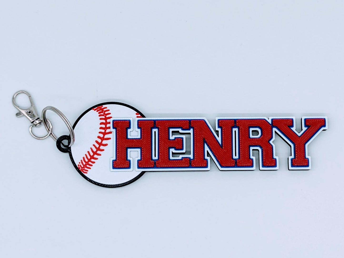 Bright red baseball bag tag with custom engraved player number and name, ready to clip onto any sports bag.